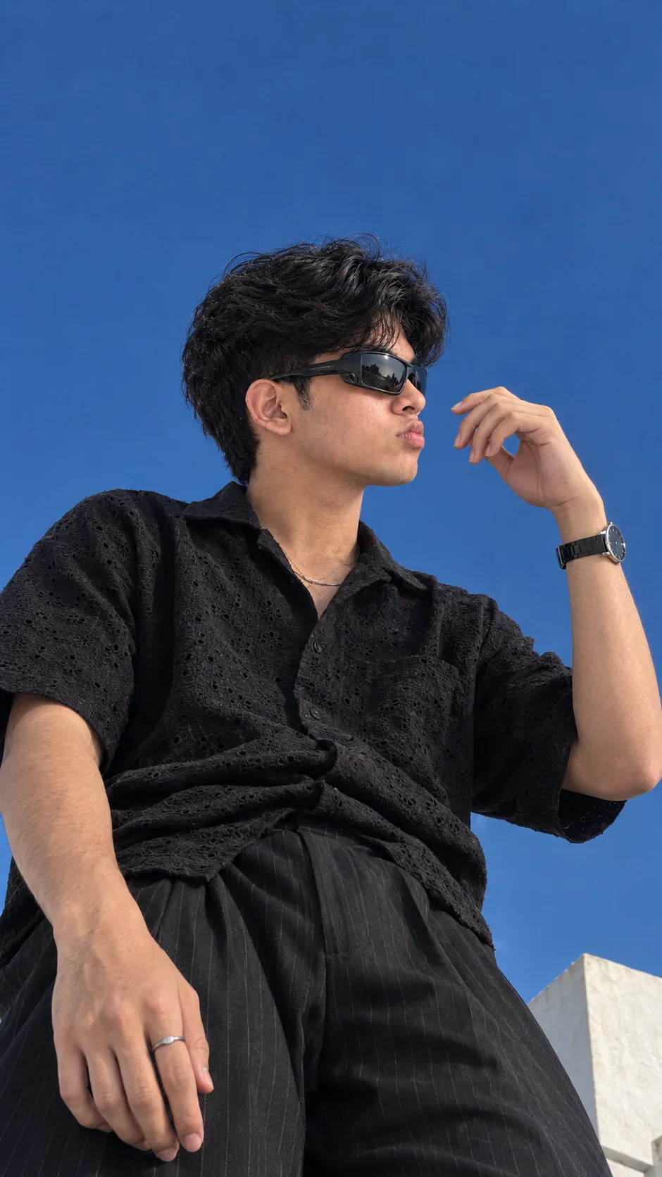 Create an ultra-realistic cinematic fashion editorial photograph of a young man captured from a dramatic low-angle perspective against a