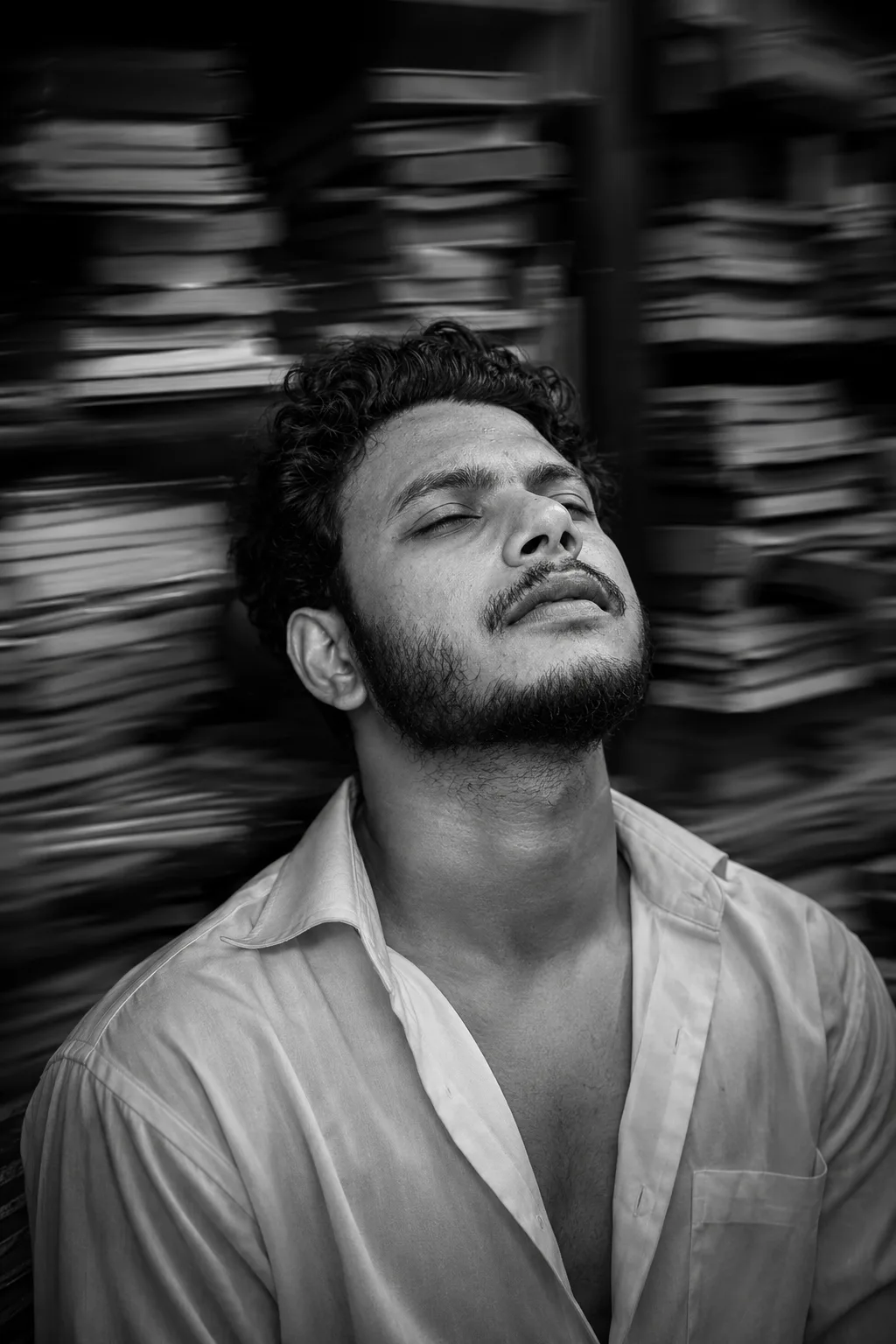 A dramatic black and white portrait of a handsome young man with his head tilted back, looking upwards with an exhausted or dreamy