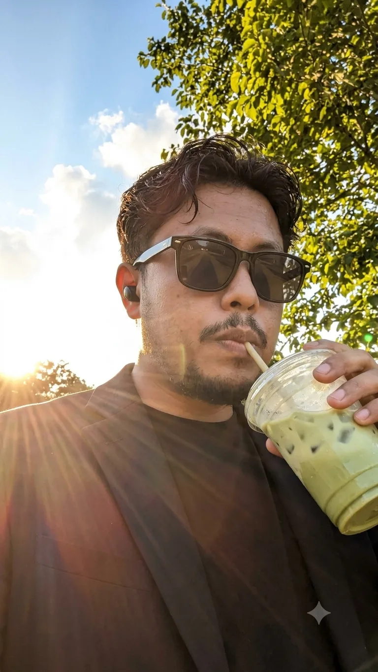 Prompt Low-angle selfie photo of a young man wearing dark square sunglasses and a wireless earbud, sipping an iced matcha latte through a