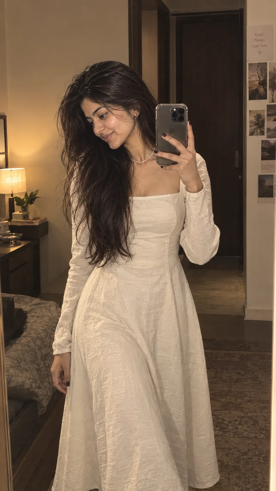 Girls Prompt 🤍❤️ A young woman with long, wavy dark hair taking a mirror selfie in a warm indoor setting.