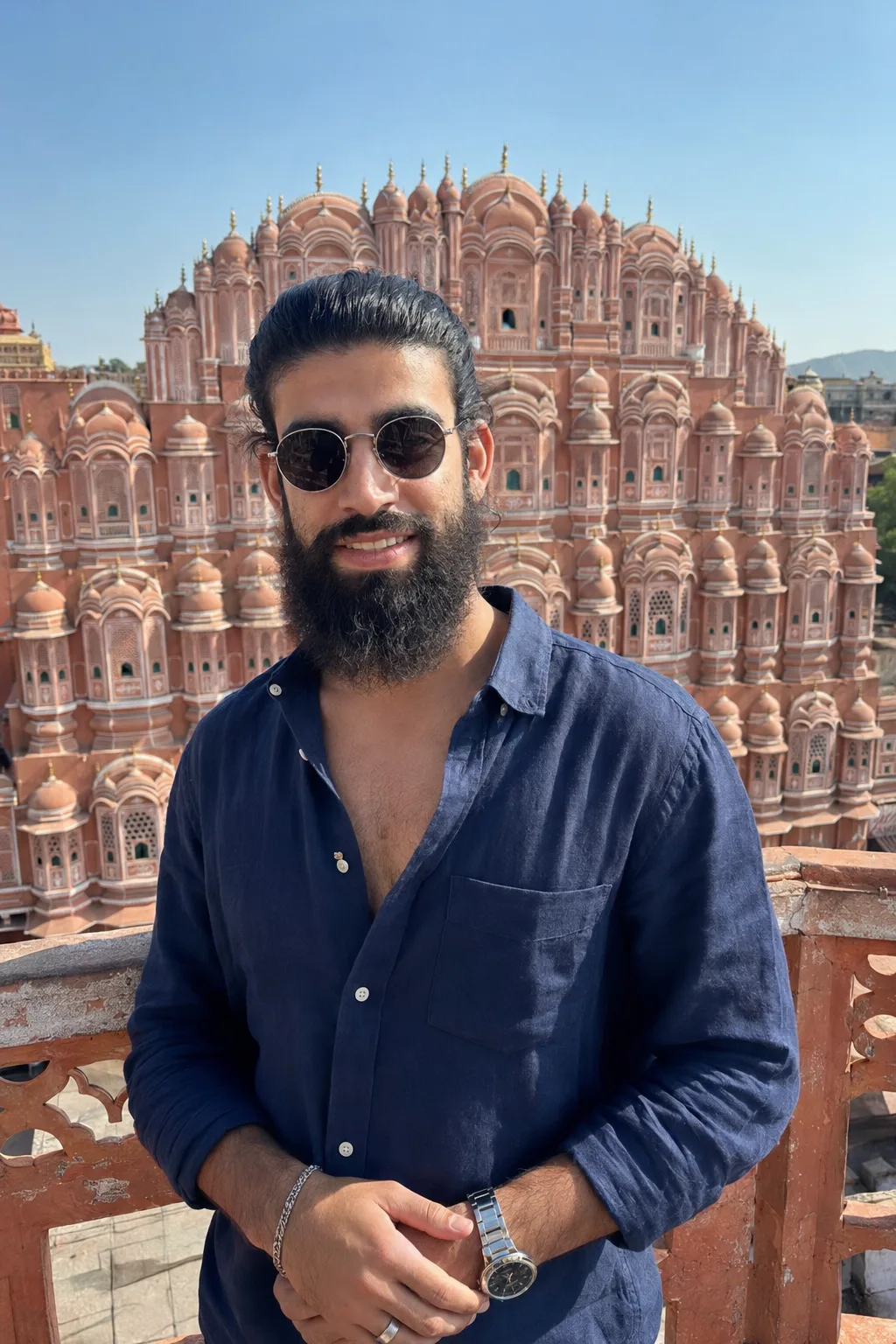 Create a highly realistic, photorealistic vertical travel portrait of a young South Asian man standing on a rooftop terrace directly in