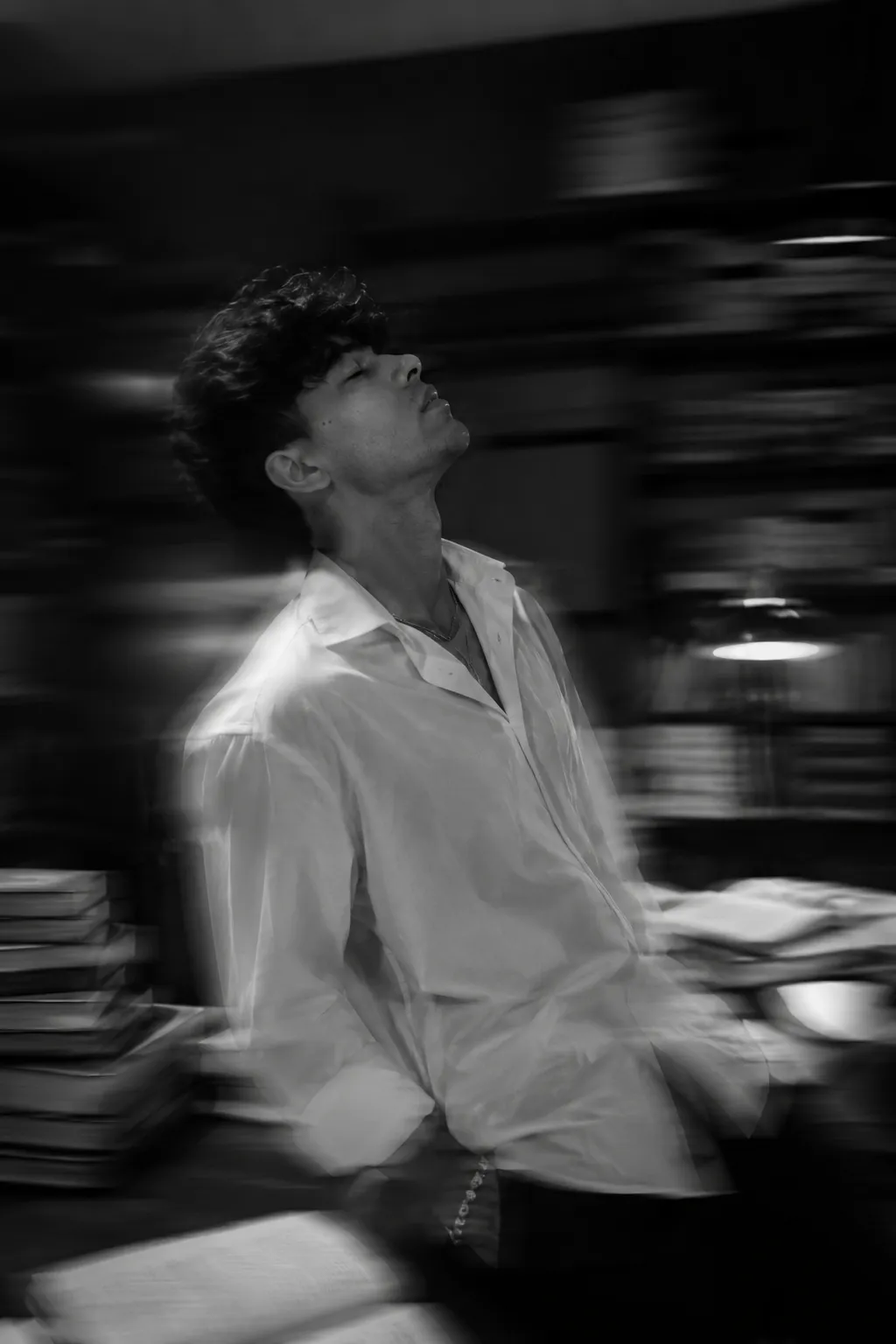 Convert this image into a Fine black and white photography of a handsome young man (using uploaded image) with dark, his head tilted back