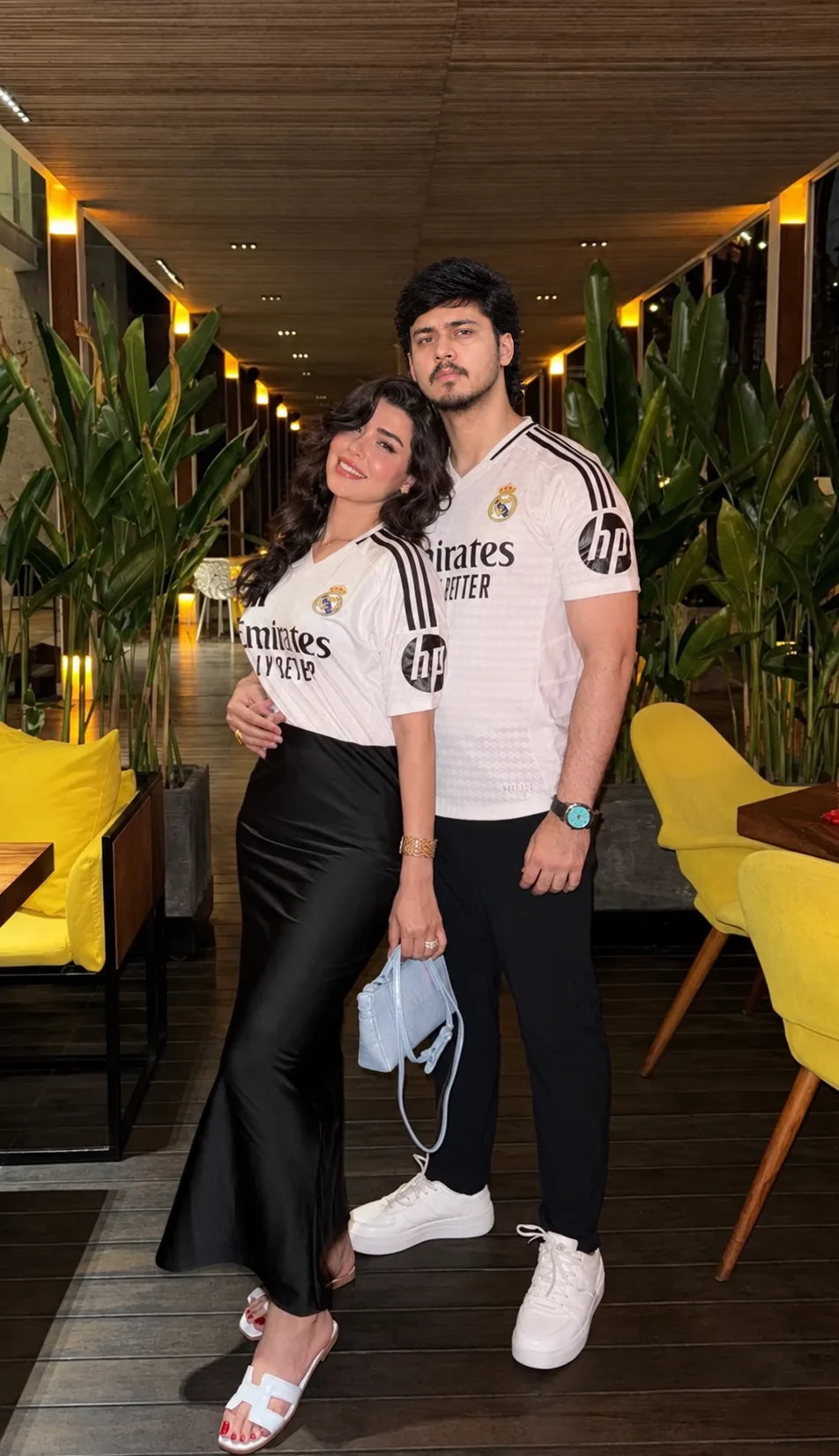 Create a highly realistic full-body couple portrait inside a stylish modern restaurant or café corridor at night.