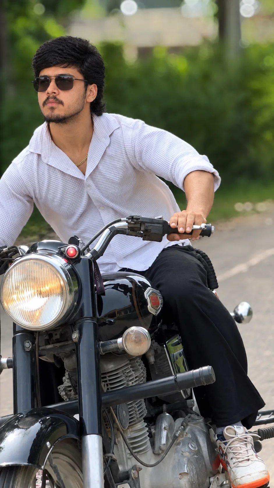 Create an ultra-realistic, high-resolution outdoor portrait of a young South Asian man confidently sitting on a classic black motorcycle on