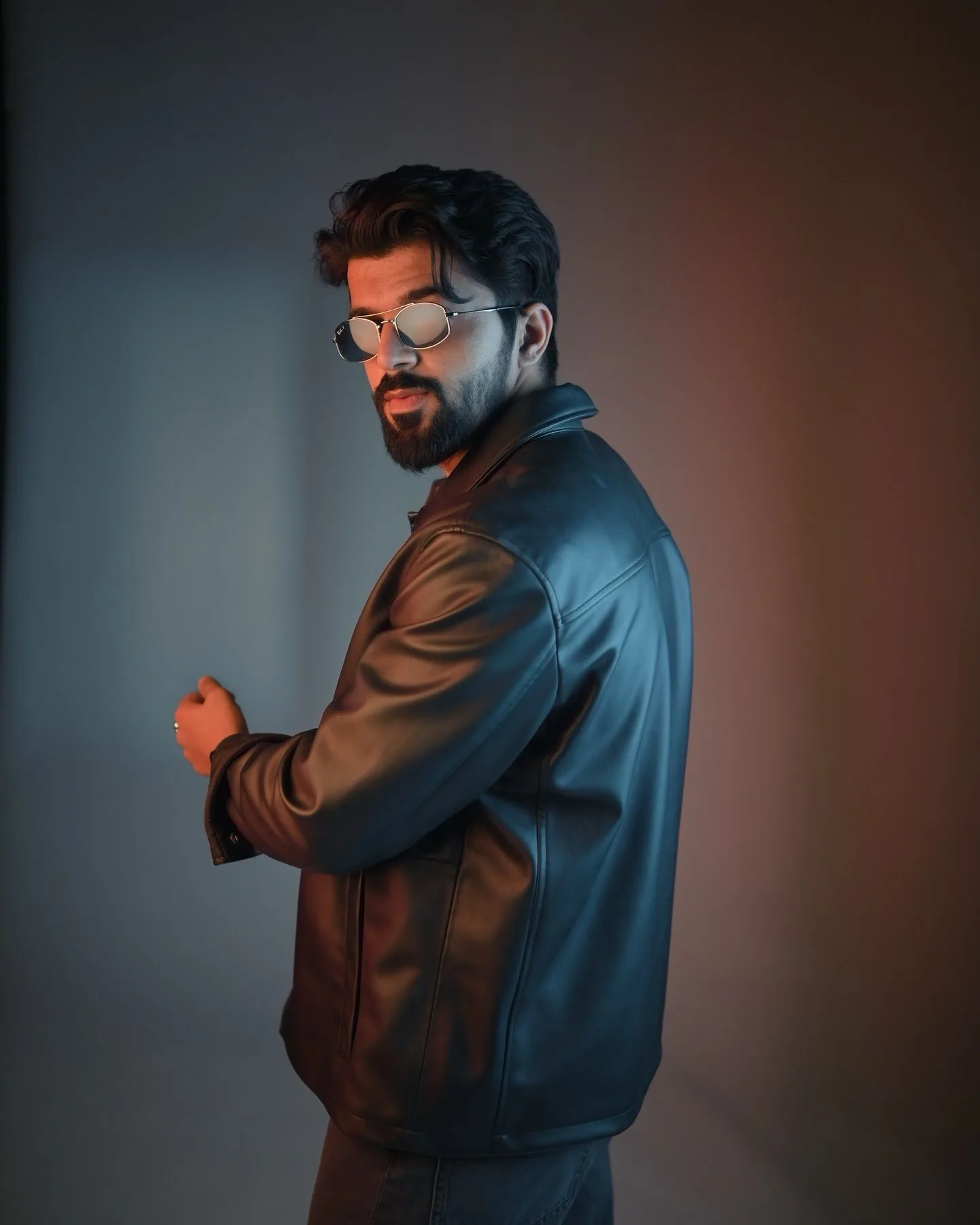 CONCEPT: Moody studio portrait featuring a male model in a black leather jacket, looking back over his shoulder in silver wire-frame