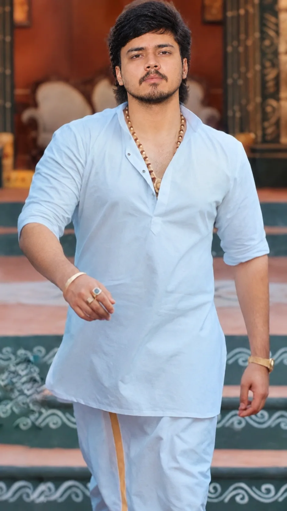 Create an ultra-realistic, photorealistic vertical portrait of a young South Asian man confidently walking toward the camera in an elegant