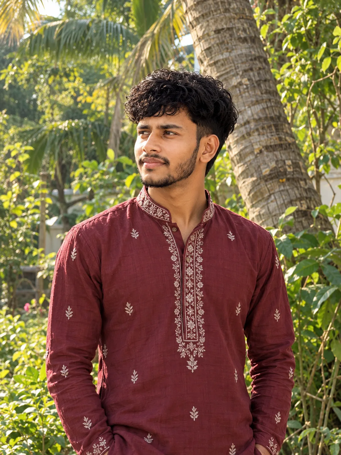 Ultra-realistic professional DSLR photograph of a slim young South Asian man standing outdoors in a lush tropical garden, captured in a