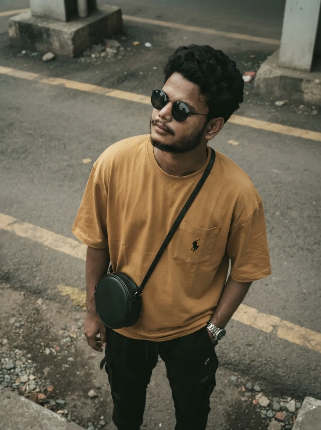 YELLOW TEE STREETWEAR BKT male lock with dark round sunglasses, looking up and to the side, oversized mustard-yellow tee with small pocket