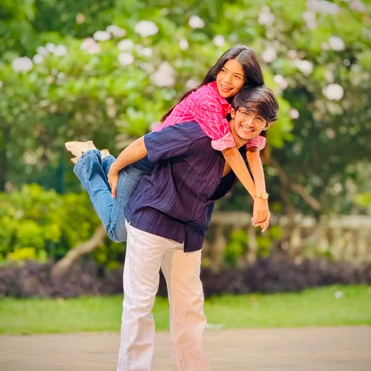 A photorealistic, high-resolution full-body outdoor lifestyle portrait of a happy, playful young South Asian couple having fun in a sunlit
