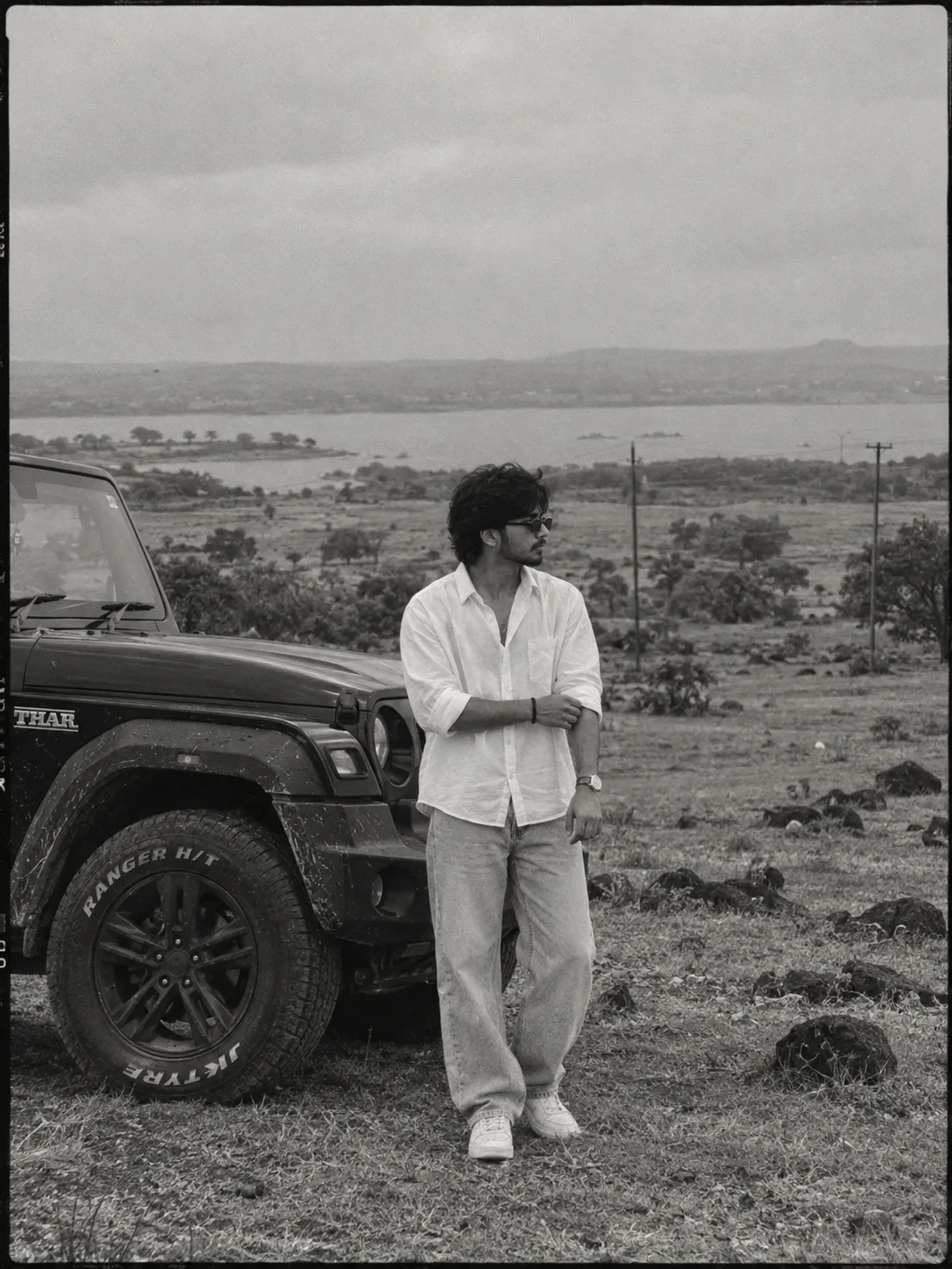 Black and white analog film photograph, photorealistic, ultra detailed, cinematic moody aesthetic, a young South Asian man in his mid-20s
