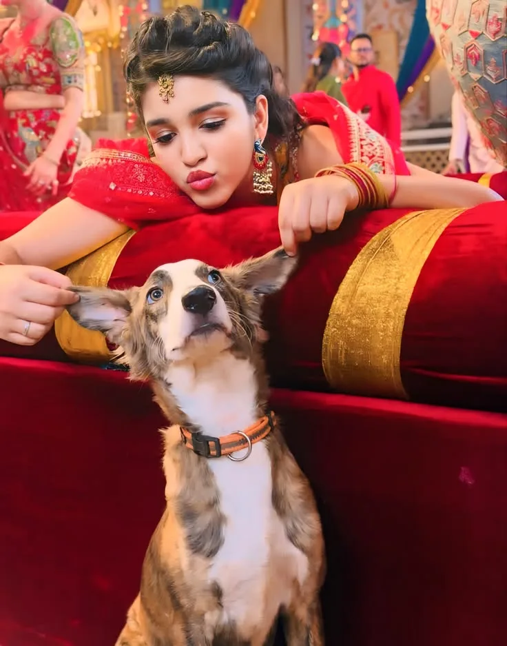 A beautiful young Indian woman in an elegant red and gold traditional outfit sitting on a decorated wedding stage, playfully holding the