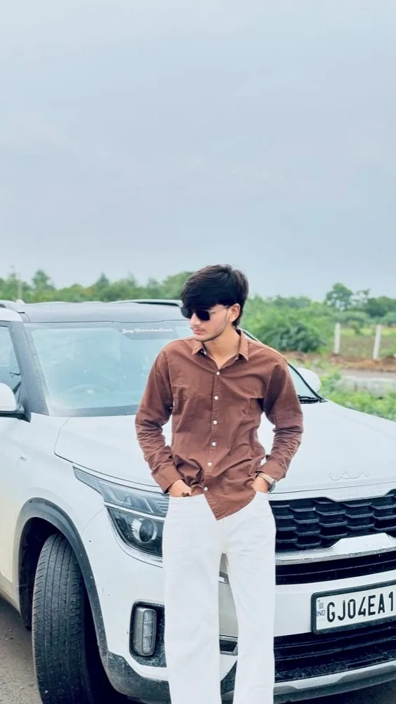 A photorealistic vertical medium-to-full shot of the young South Asian man from the reference image, faithfully preserving his exact