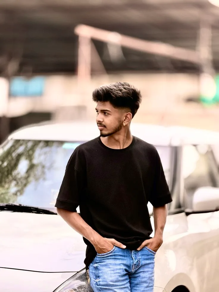 A photorealistic vertical medium shot of the young South Asian man from the reference image, faithfully preserving his exact recognizable