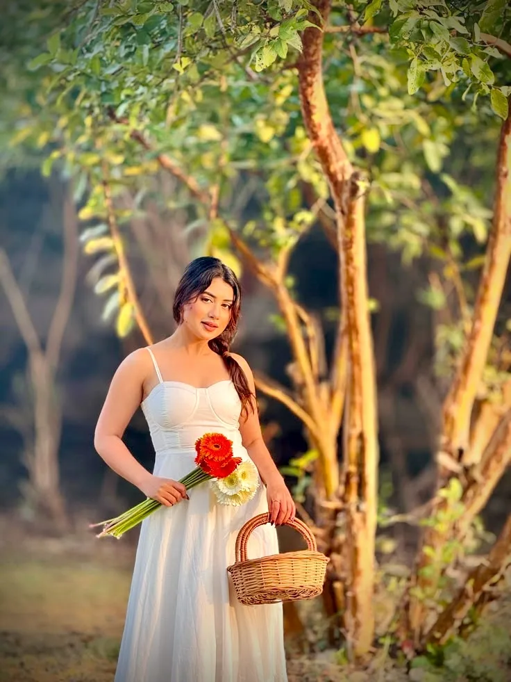 A photorealistic medium-long shot of a beautiful young South Asian woman standing in a sun-dappled grove, strictly preserving the exact