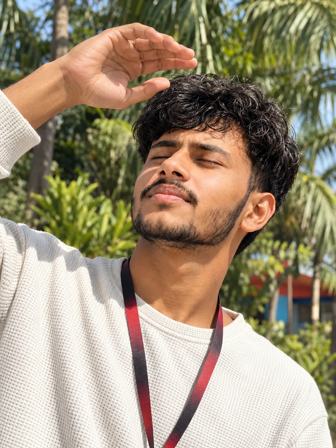 Ultra-realistic professional DSLR photograph of a young South Asian man in a tight vertical close-up outdoor portrait, captured from a low,
