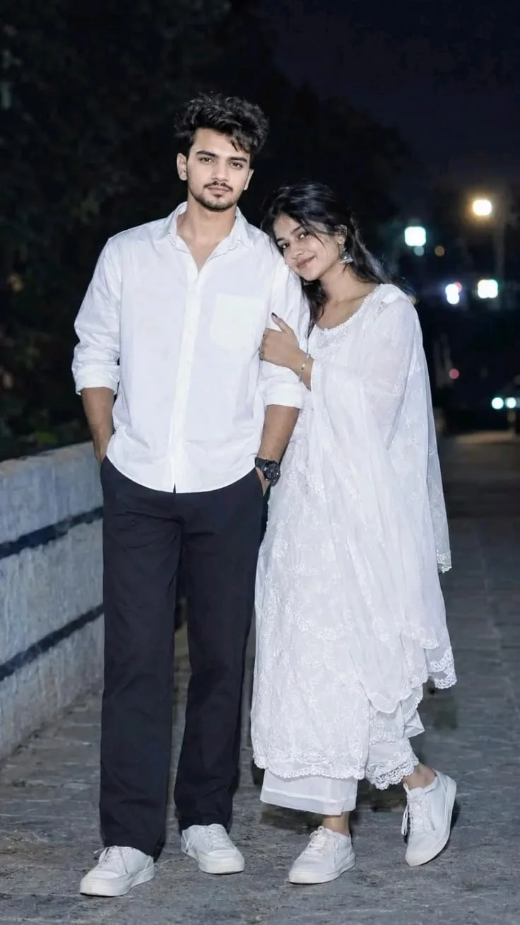 A photorealistic full-body vertical portrait capturing the young South Asian couple from the reference image, faithfully preserving their