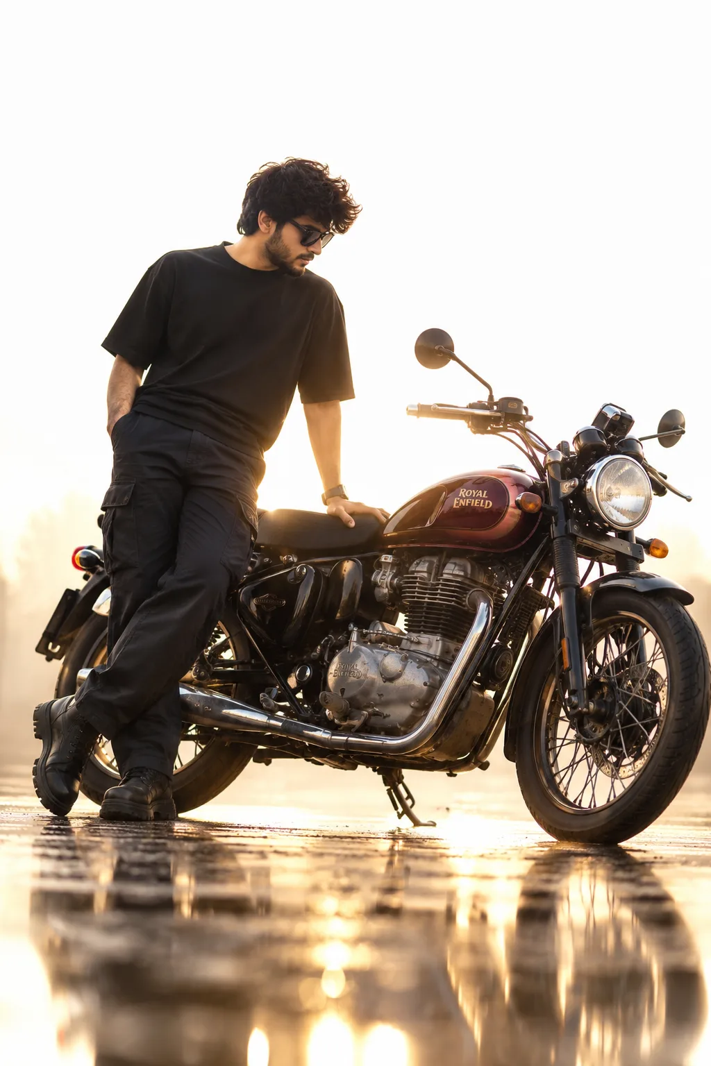 A stylish young man with curly black hair, moustache and beard, wearing black sunglasses, a loose black t-shirt, dark cargo pants and