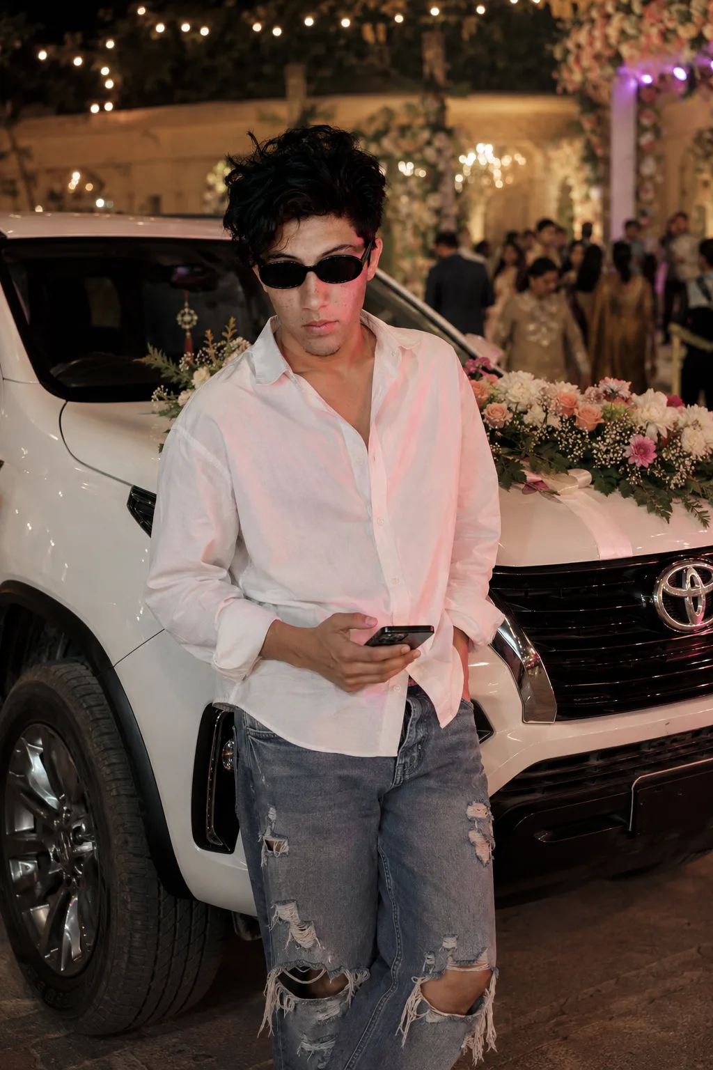 Create Effortlessly stylish mid-shot of a very handsome young boy with wavy fringe hairstyle(face reference) leaning on a white forchunar