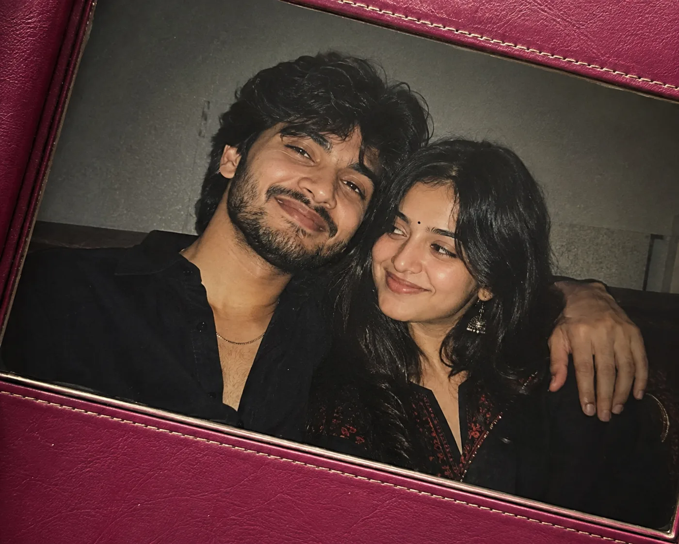 Create a photorealistic close-up candid photograph of two young Indian adults, a man and woman, seated closely and leaning affectionately