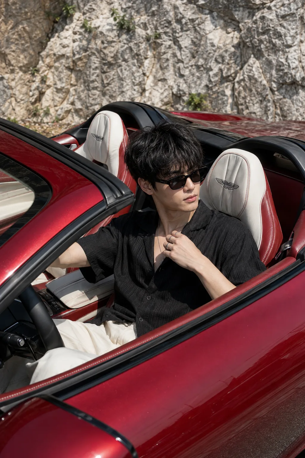 Create an ultra-realistic, premium cinematic automotive lifestyle portrait of a stylish young male sitting naturally inside the driver’s