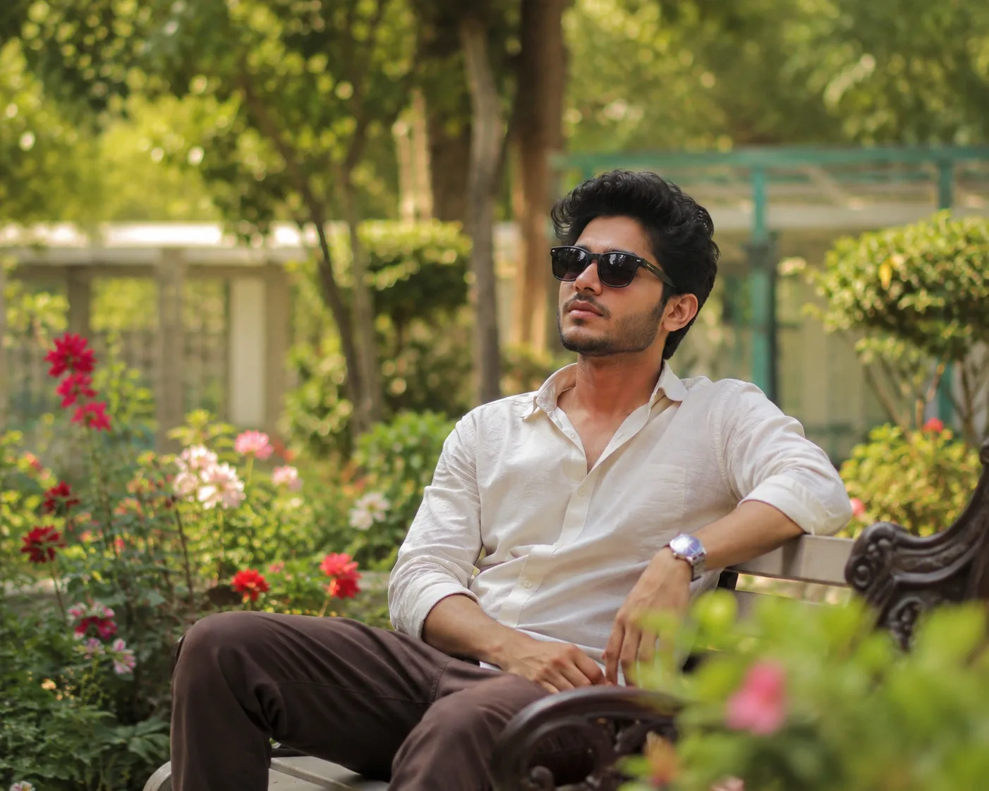 Create a highly realistic photo of a man sitting naturally in a beautiful garden.