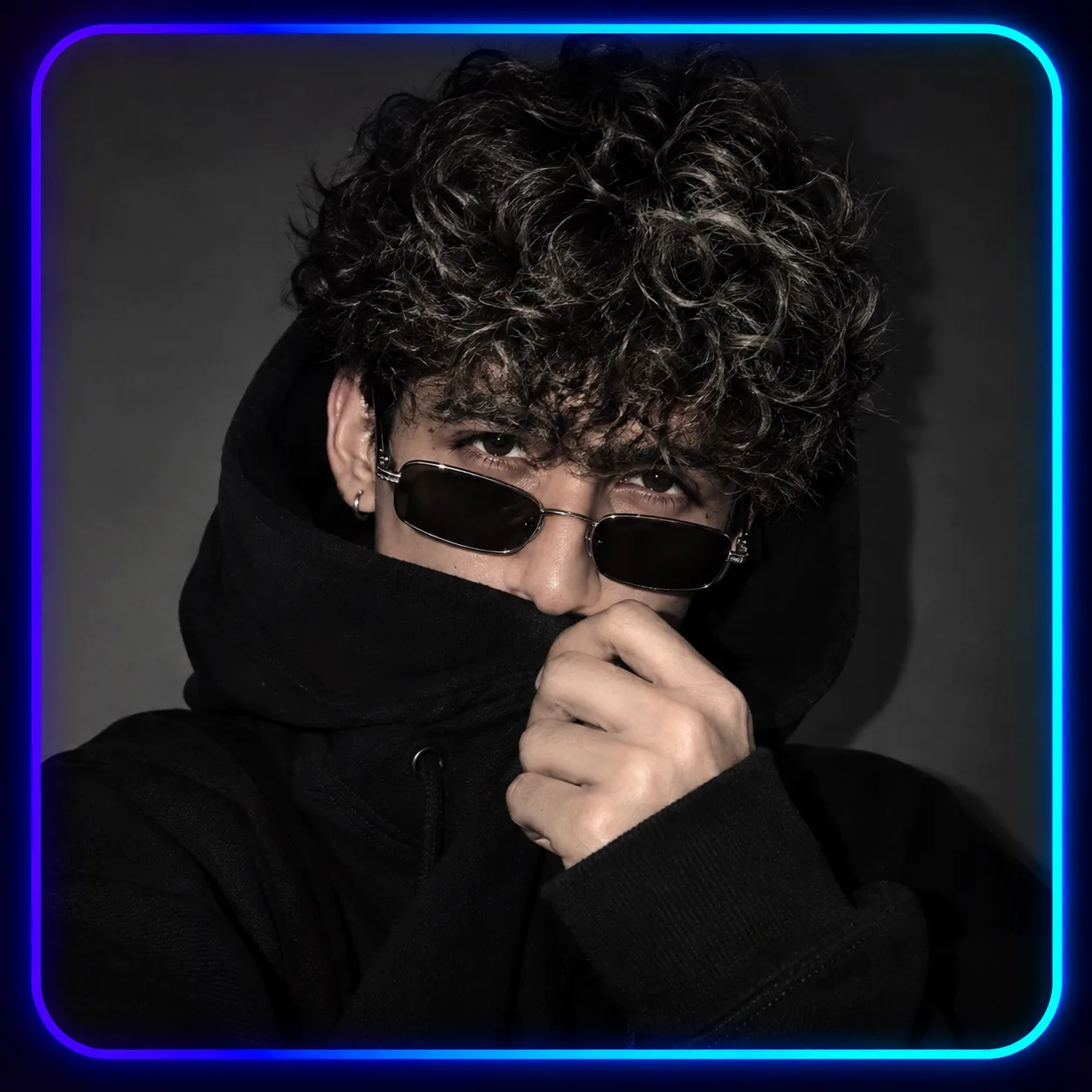 Ultra-realistic mysterious trendy young man portrait, black oversized hoodie with high collar covering lower face, hand holding hoodie near