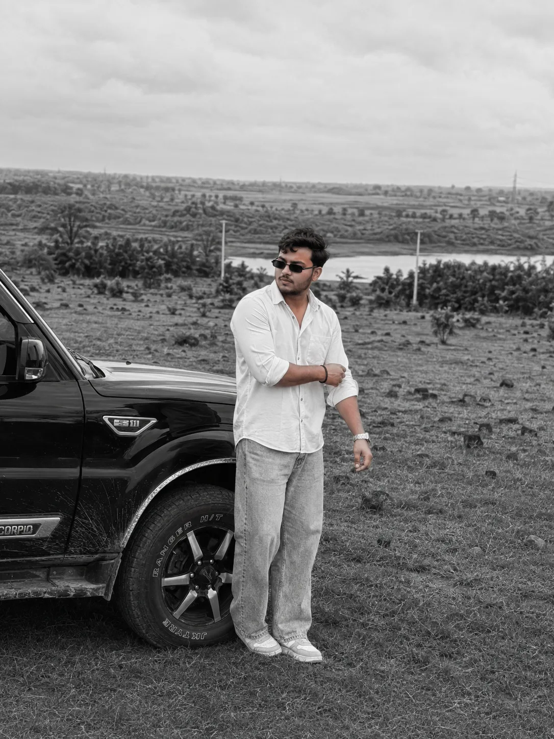 Black and white analog film photograph, photorealistic, ultra detailed, cinematic moody aesthetic, a young South Asian man in his mid-20s