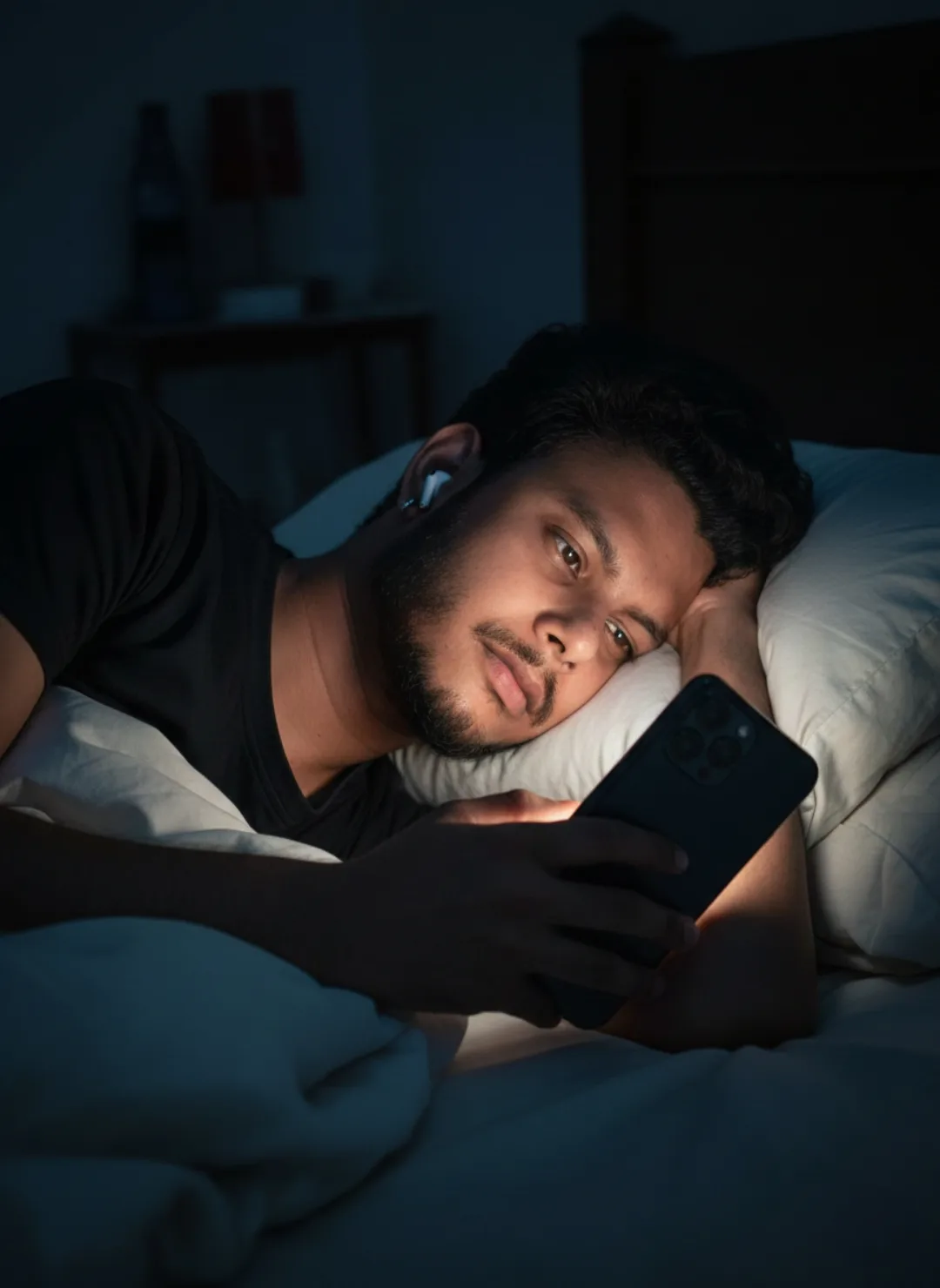 > A realistic, cinematic night portrait of a 26-year-old Indian man with short black hair, a neatly trimmed beard, and a black t-shirt,