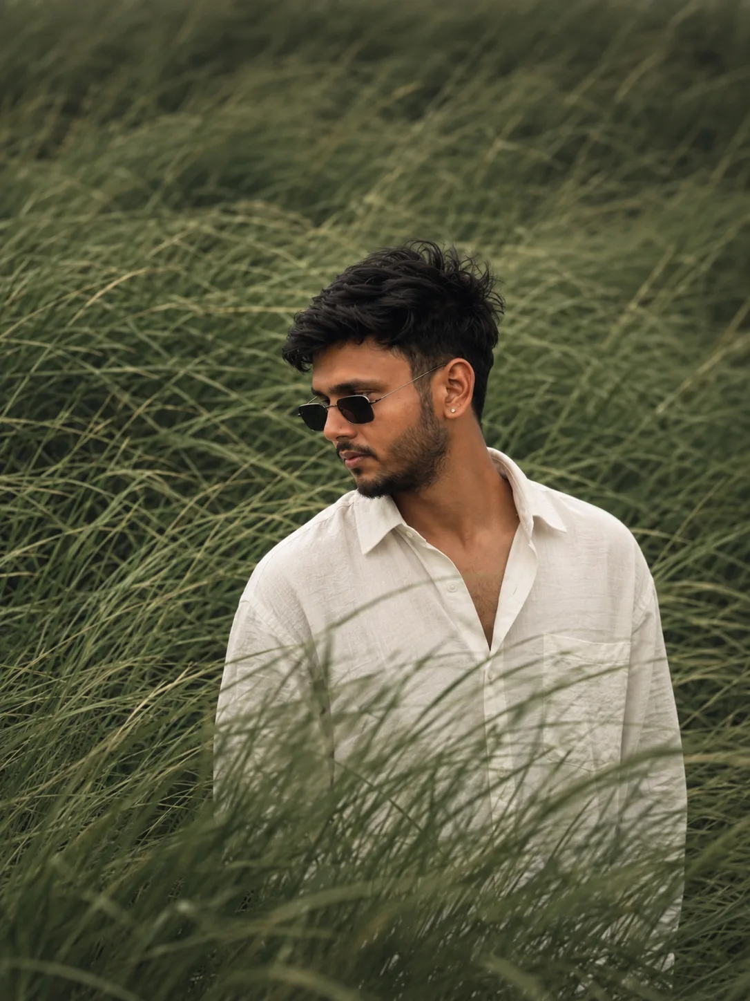 > Create an ultra-realistic cinematic outdoor portrait of a young adult South Asian man, closely inspired by the uploaded reference image