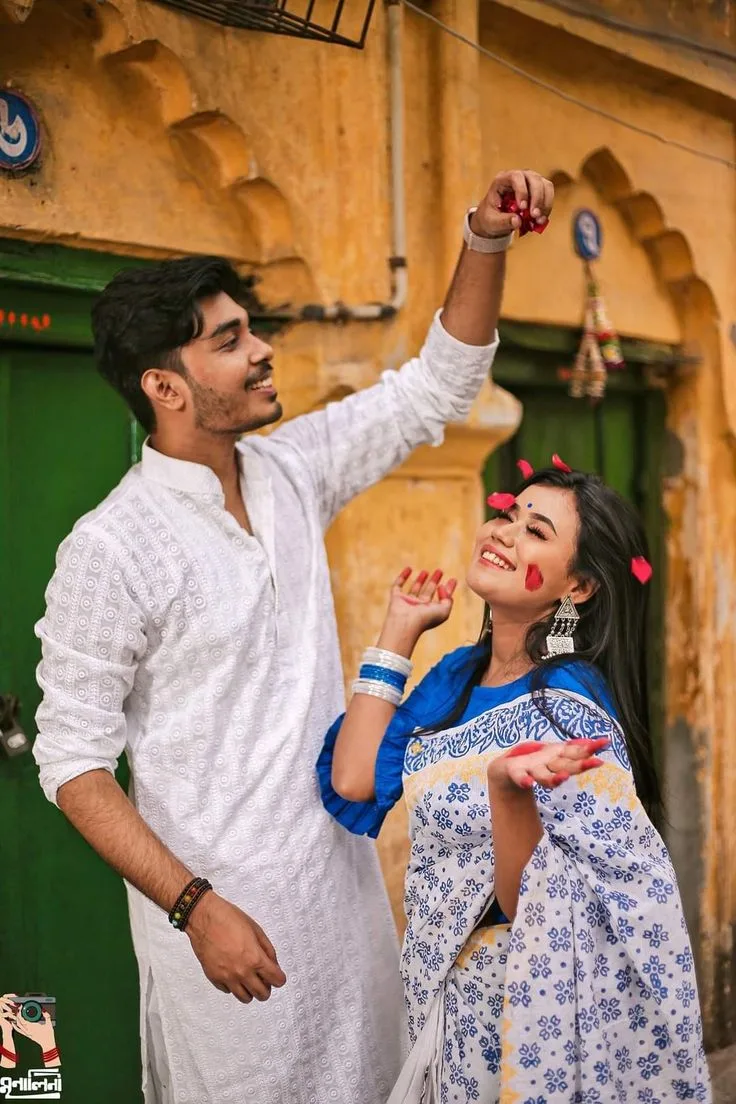A photorealistic vertical medium shot of the young South Asian couple from the reference image, faithfully preserving both subjects'