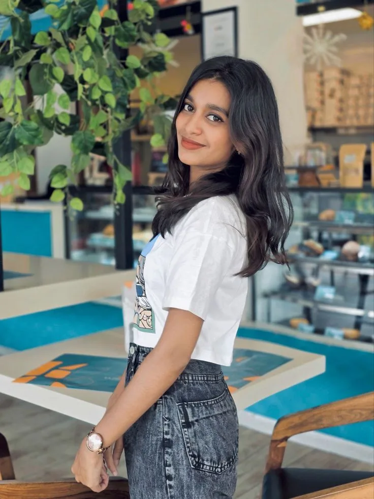 A photorealistic vertical medium shot of the young South Asian woman from the reference image, faithfully preserving her recognizable