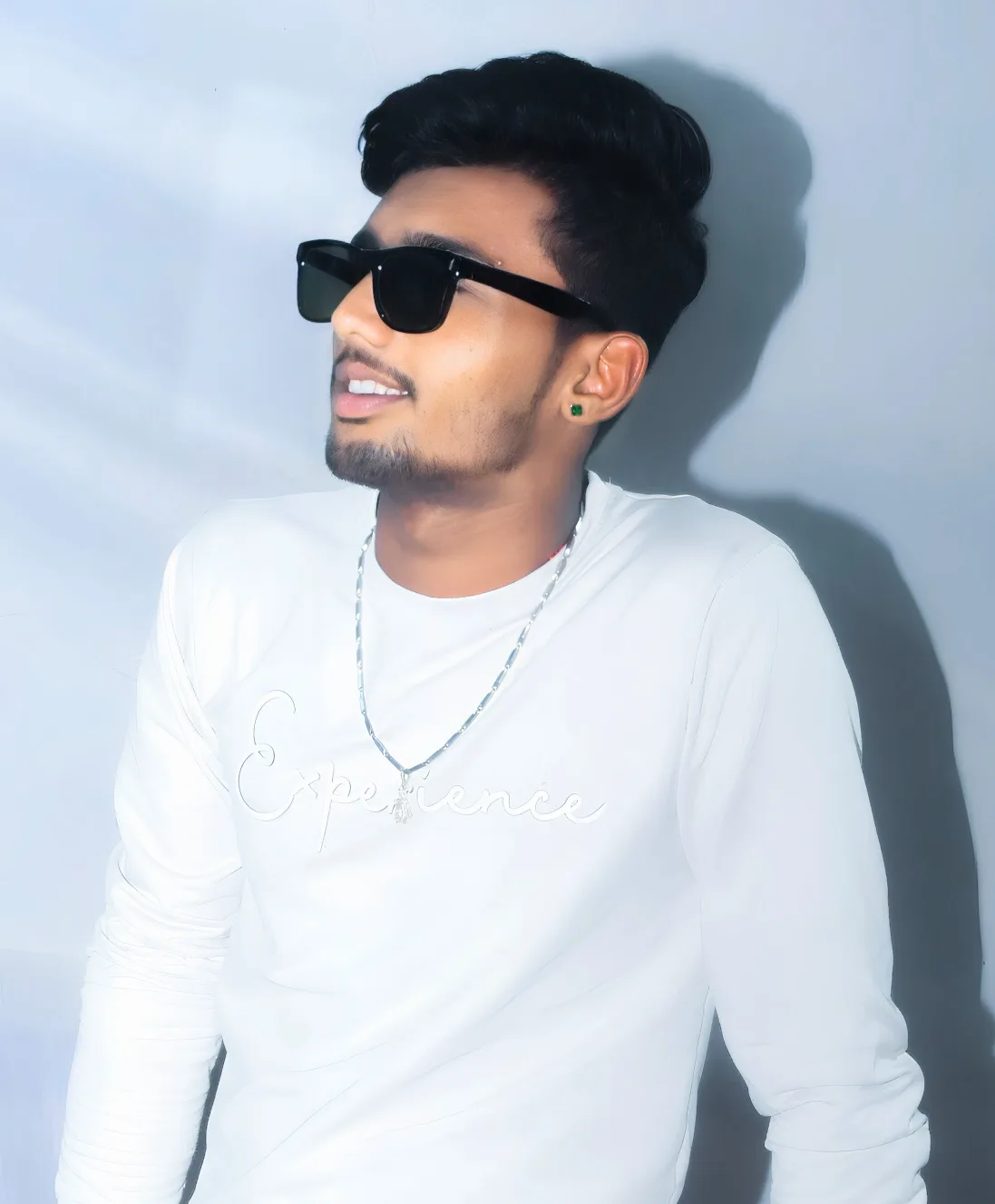 Ultra-realistic high-quality vertical portrait photograph of a young South Asian man, framed from the waist/chest up, standing indoors