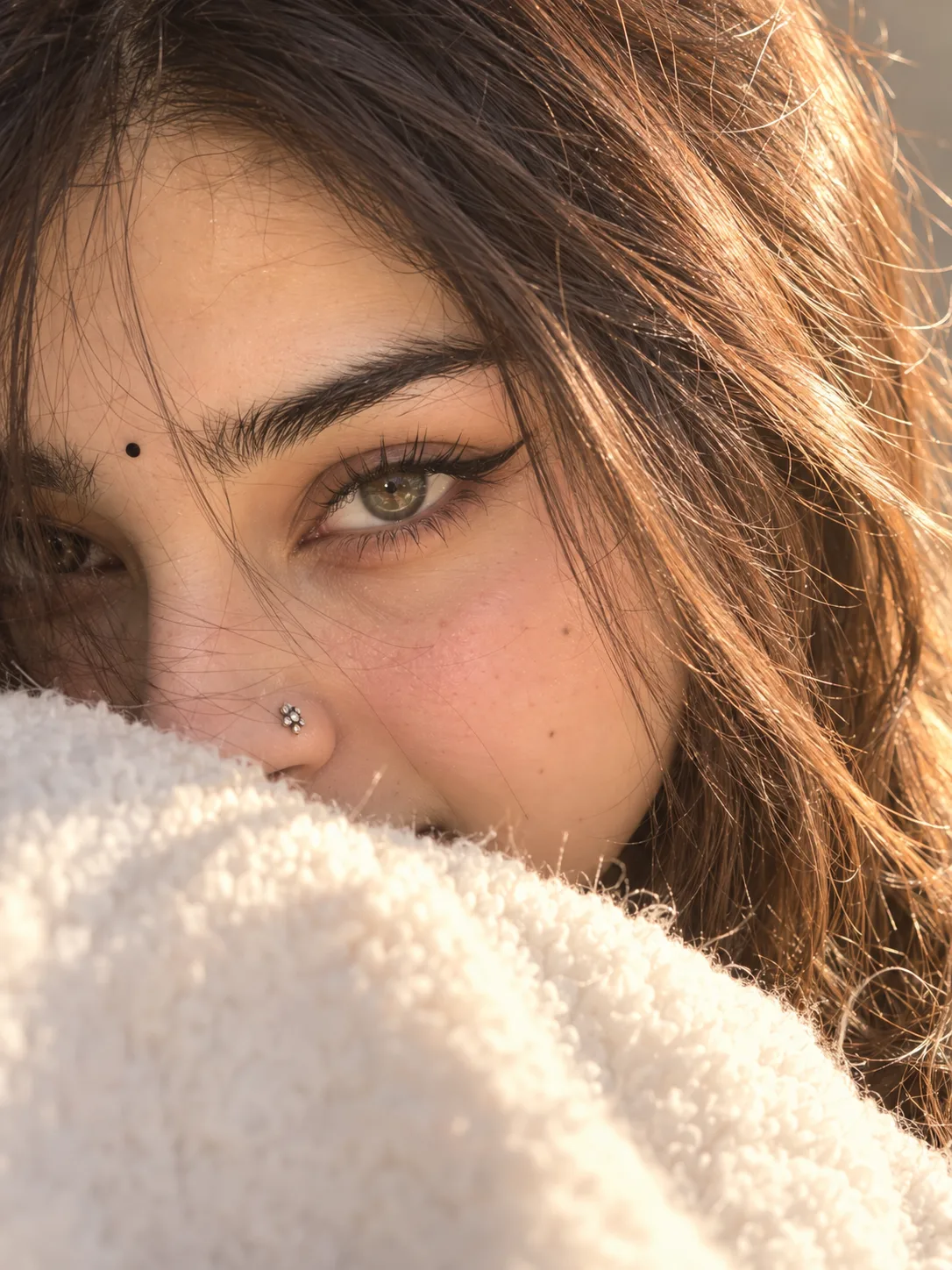 Close-up portrait of a beautiful young woman, only half face visible, intense hazel green eyes with long thick eyelashes, sharp winged