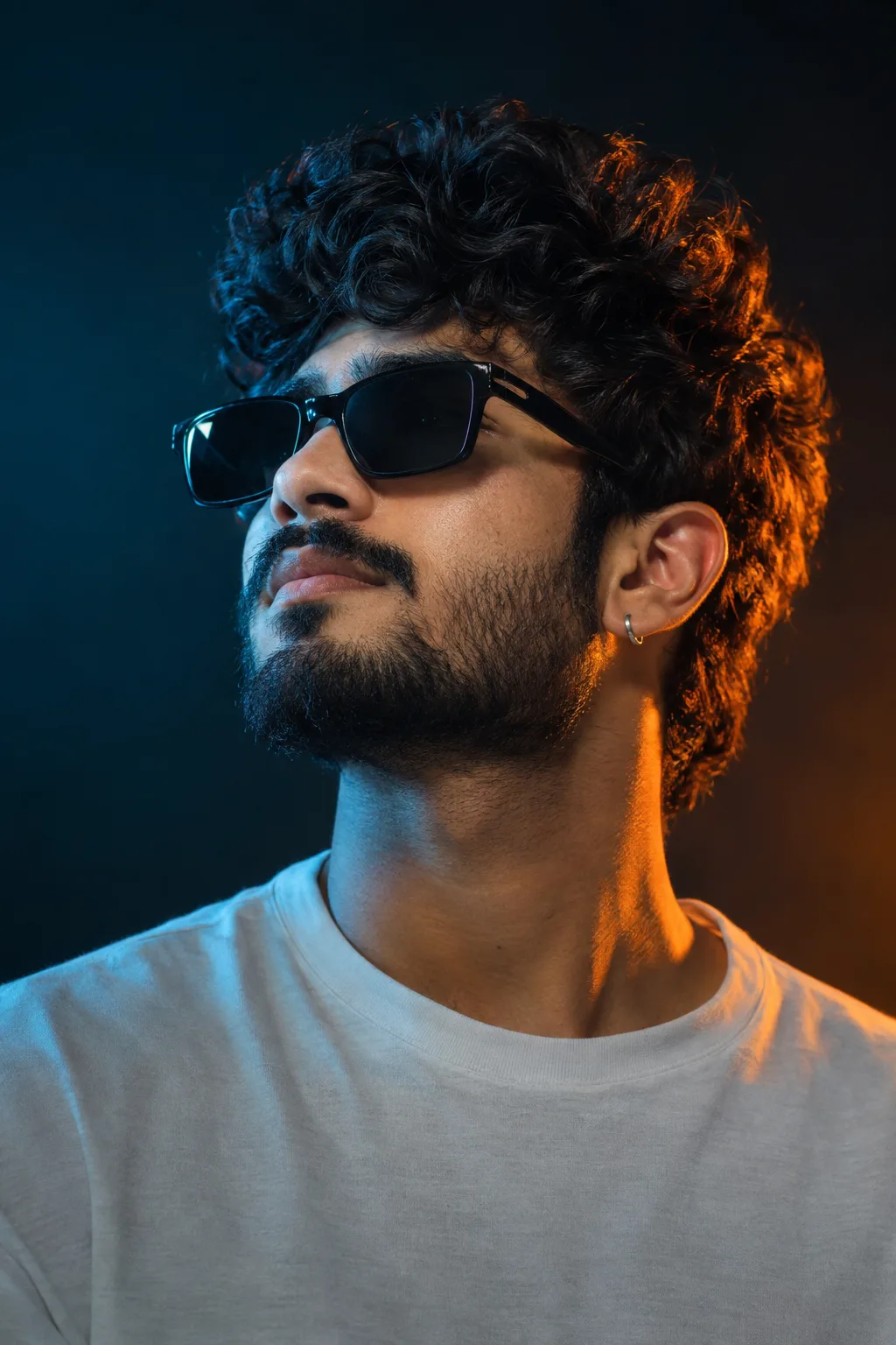 2/6 PROMPT Close-up cinematic studio portrait of a stylish young man with curly dark hair, a well-groomed beard and mustache, wearing black