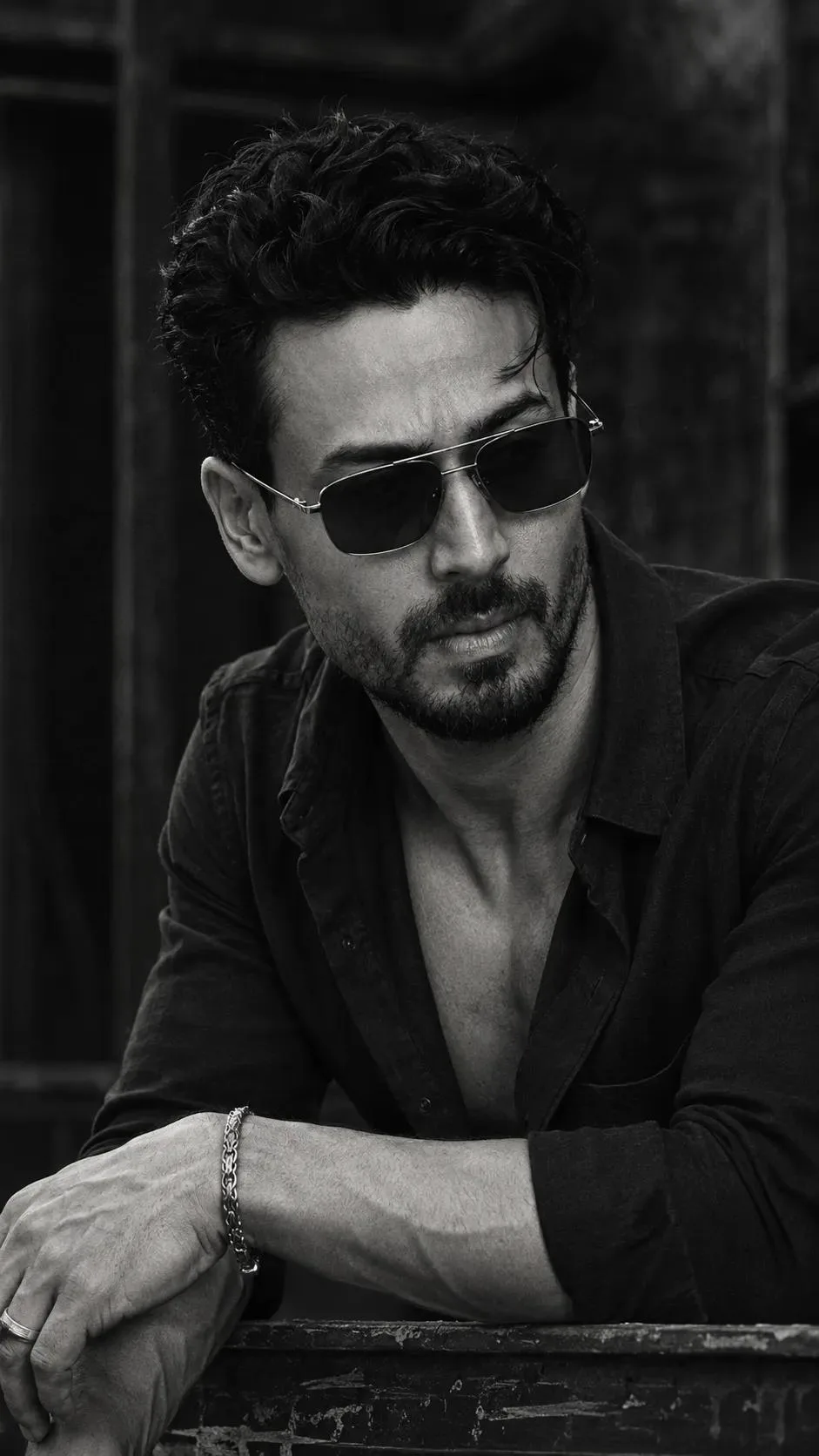 A black and white, gritty portrait of a man with a beard and messy hair, looking intensely to the right.