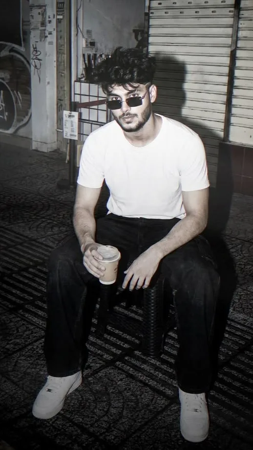 A photorealistic vertical night portrait of the young South Asian man from the reference images, preserving his exact facial identity,