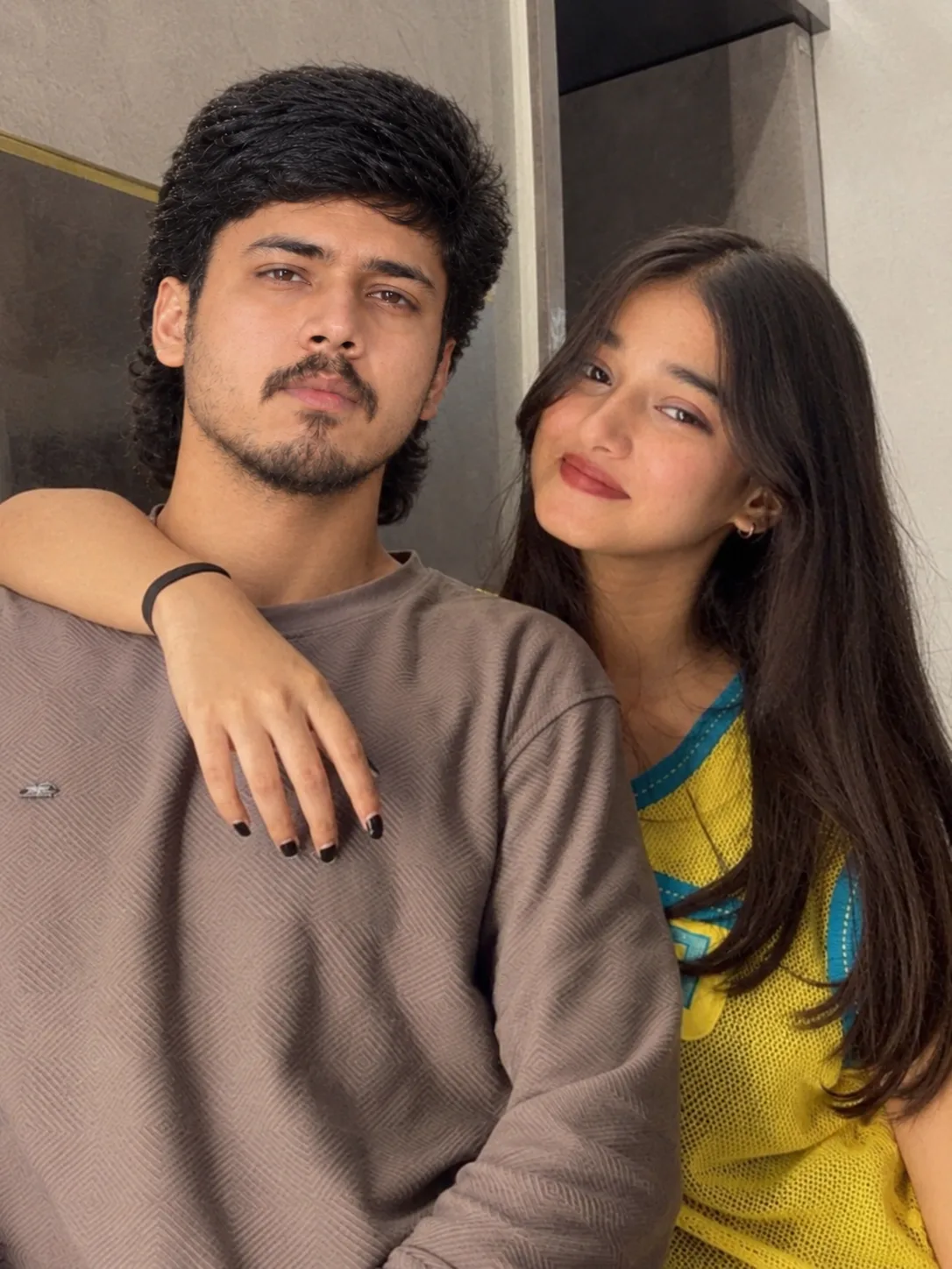 Create an ultra-realistic candid smartphone selfie of a young South Asian/Indian couple standing very close together.