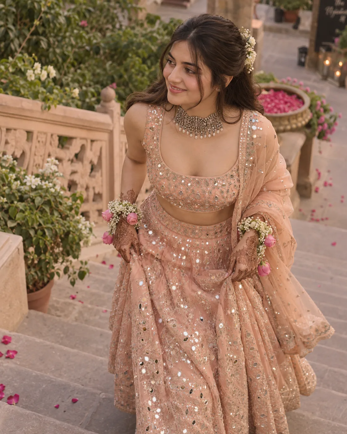 Geminismiling as she ascends a set of outdoor stairs, dressed in elegant traditional Indian attire.