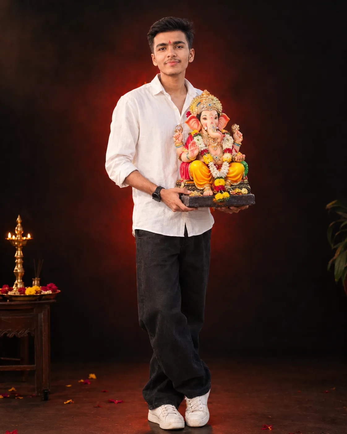 A high-quality studio portrait of a young Indian man, same person as uploaded image, holding a colorful Lord Ganesha idol during Ganesh