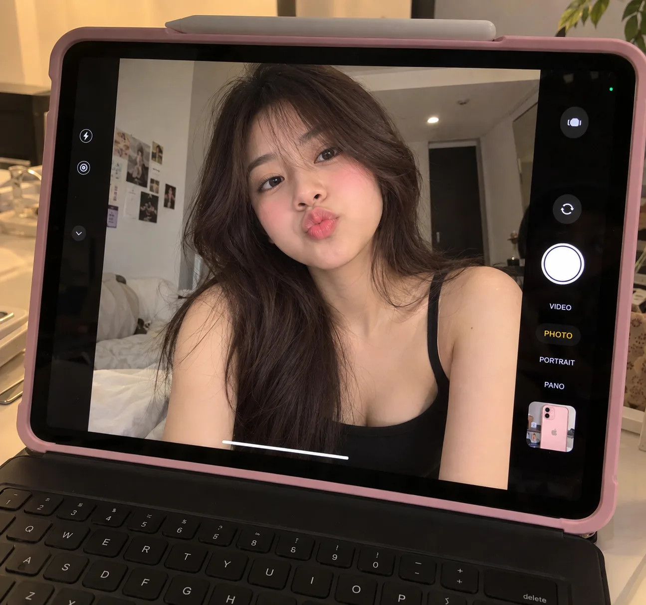 A high-quality photo taken of an iPad screen displaying a cute, realistic selfie of an Asian young woman with long dark brown hair and soft