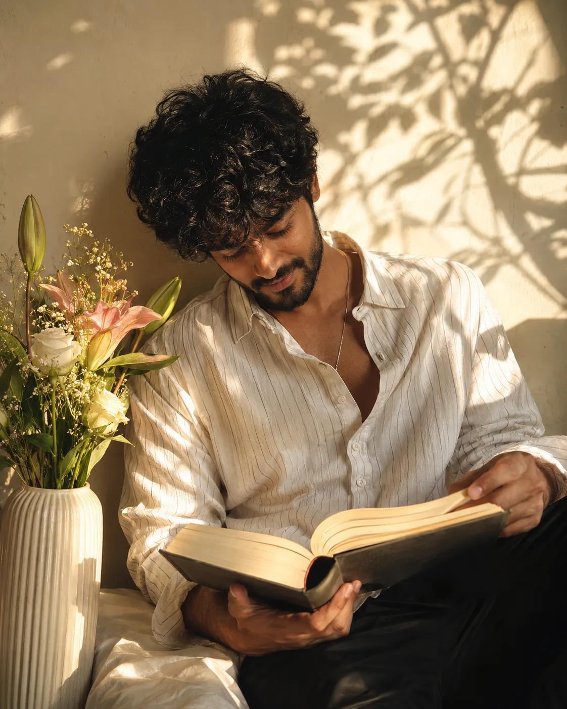 Create an ultra-realistic, intimate lifestyle editorial portrait of a handsome young South Indian man sitting casually indoors beside a