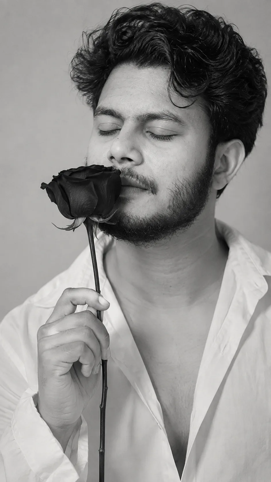 Here is the detailed prompt generated from the image: "A candid black and white photograph capturing a young South Asian man with