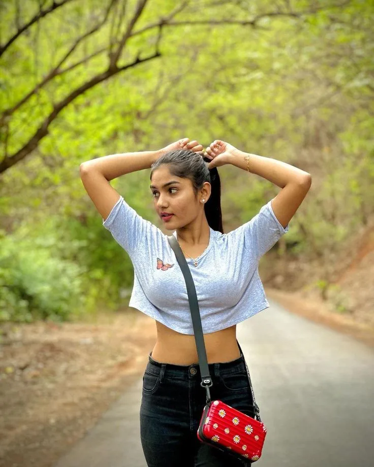 A photorealistic vertical medium shot of the young South Asian woman from the reference image, faithfully preserving her recognizable