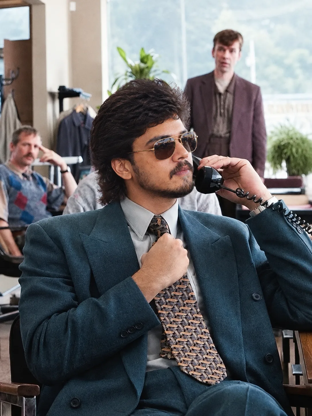 Create an ultra-realistic cinematic portrait of a stylish young Indian man seated confidently in a sophisticated vintage-modern office or